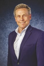 A man in a suit in front of a blue background