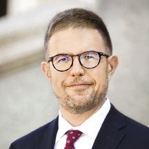 A man wearing glasses and a suit with a red tie