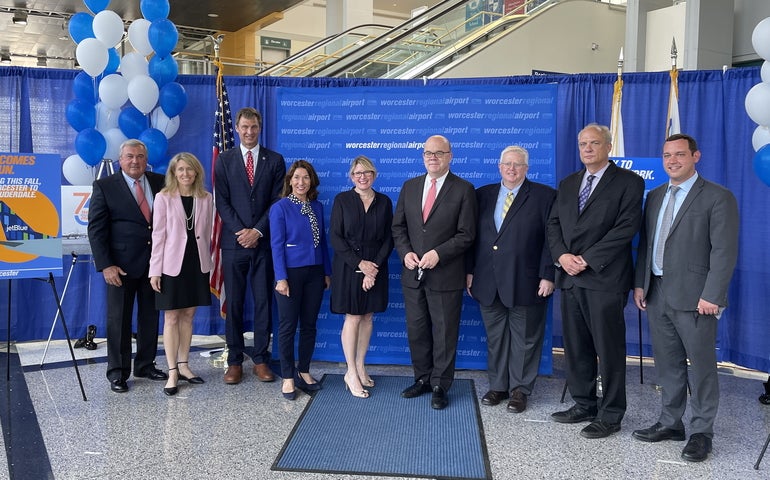 A group of people stand in front of a blue background