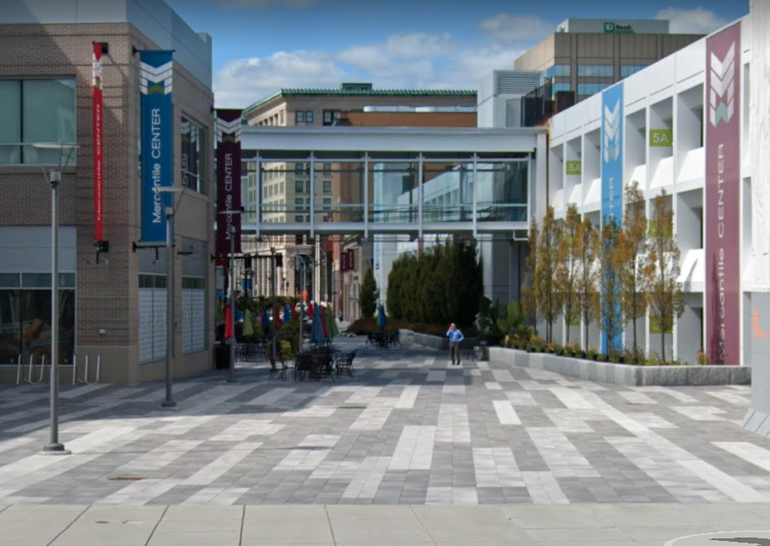 A pedestrian area with a glass pedestrian bridge running above it