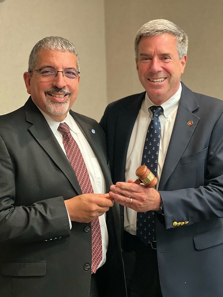 Two men in suits passing a gavel left to right