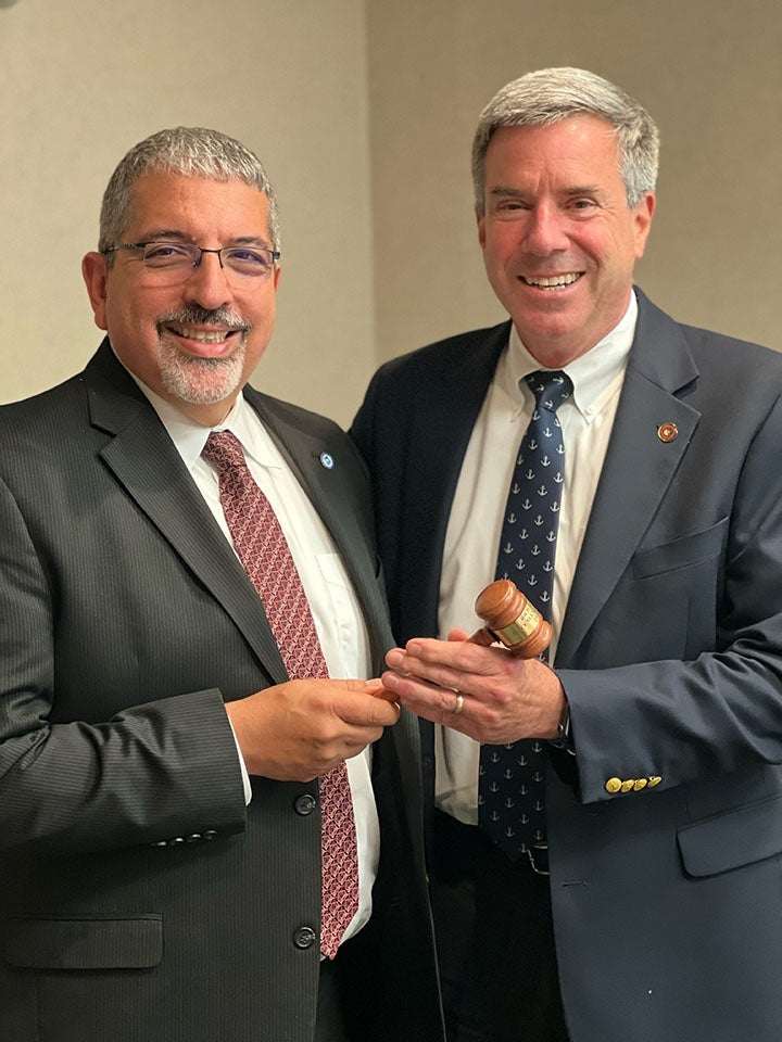 Two men in suits passing a gavel left to right