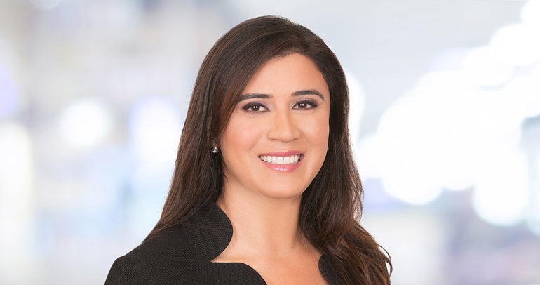 A woman with dark hair wears a black top.