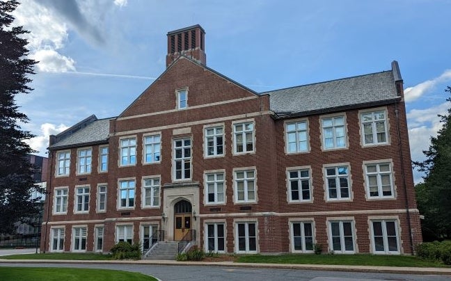 A brick building with a pointed roof with many windows.