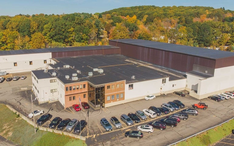 Aerial photo of a manufacturing building sitting in front of a wooded area
