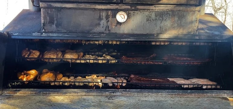 A BBQ smoker full of various meats