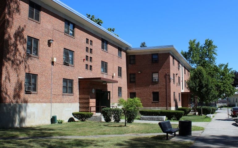 Two three-story brick residential buildings with a small lawn in front