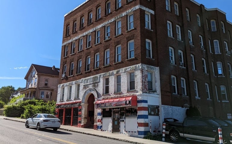 A brick building with an arched entryway and red awning to the side