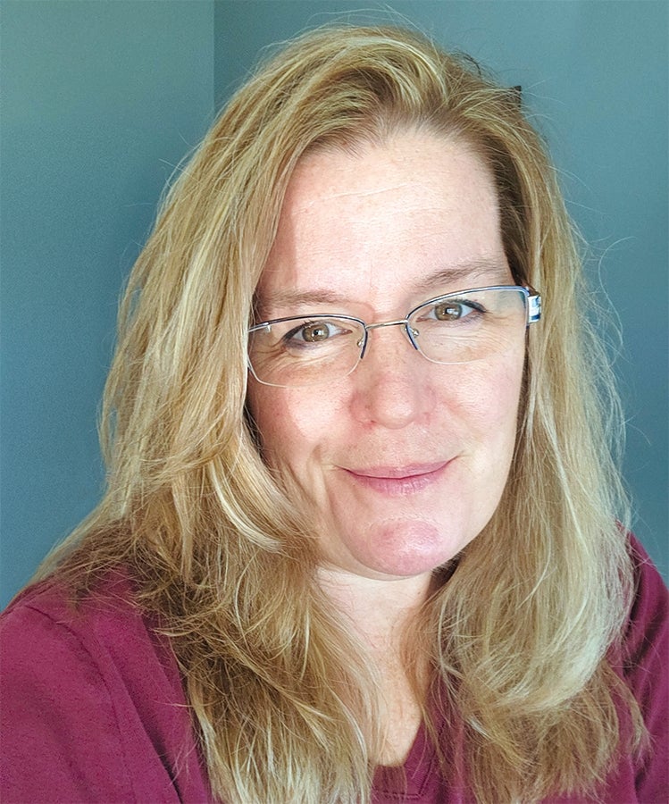 A headshot photo of a woman with glasses