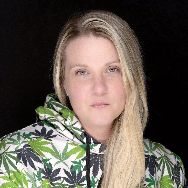 A woman wears a sweatshirt with marijuana plants on it.