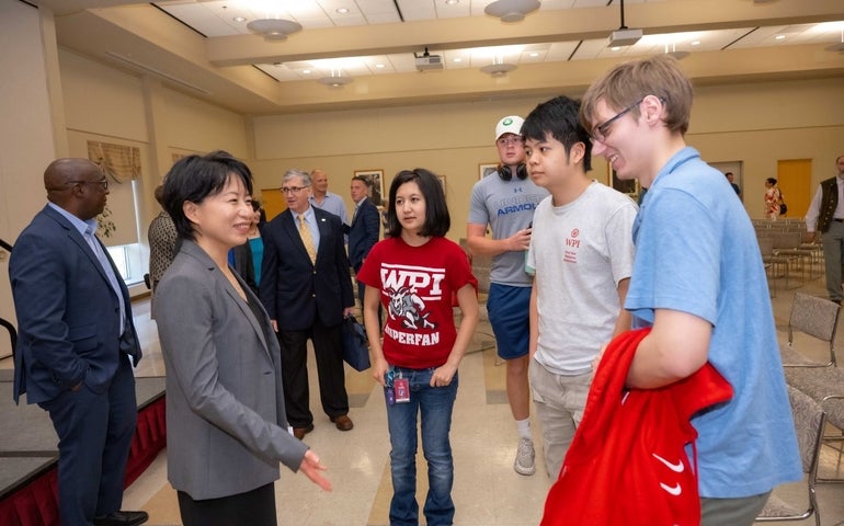 Grace Wang speaks with a group of students with administrators and faculty in the background