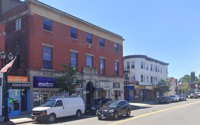 A red brick building and a white-sided building with retail on the first floor.