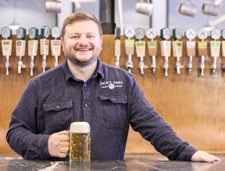 A man stands at a bar with a beer in his hand.