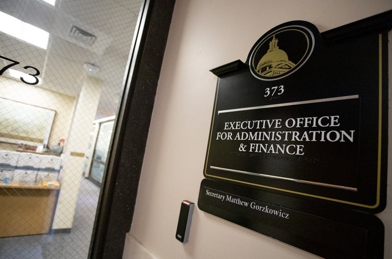 A sign for the Executive Office of Administration and Finance is posted on a wall outside a glass door.