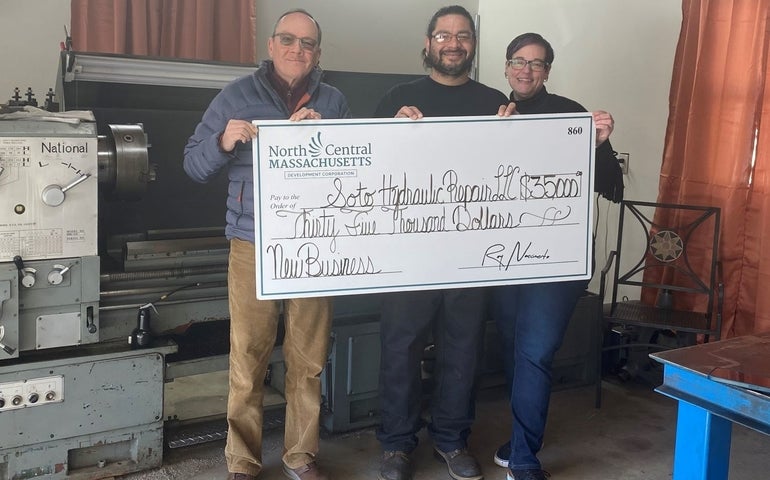 Three people holding large check