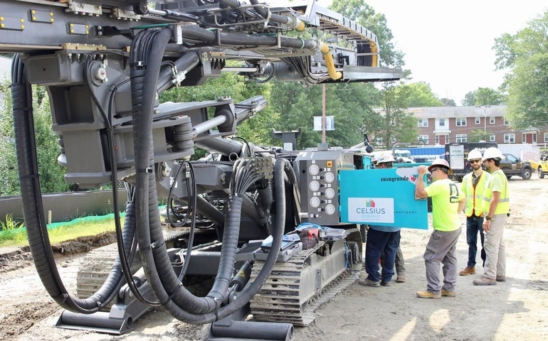 Five workers look at a piece of large equipment.