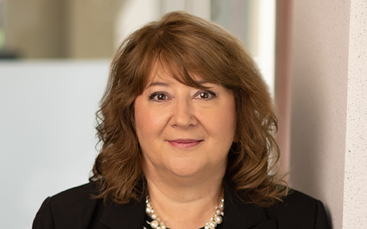 A woman wearing a black suit jacket and a necklace 