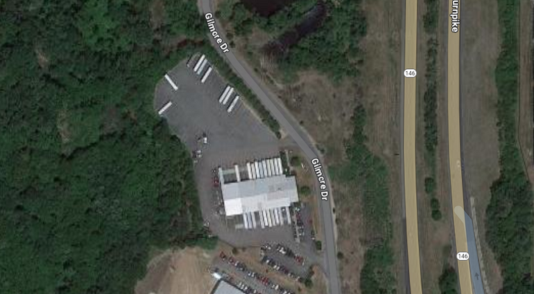 A satellite image of a white-roofer building sitting in the middle of a large paved area, with