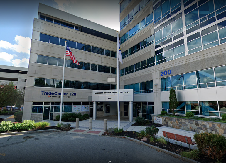 A large grey building with two flag poles in front.