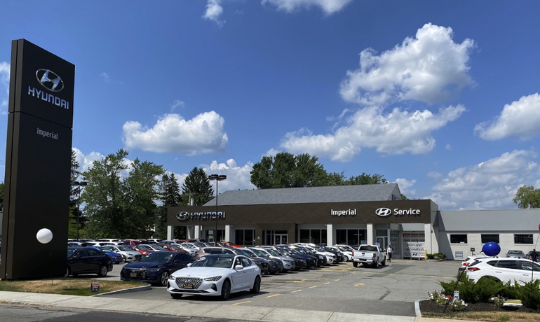 A car dealership with many cars parked in front of a one story buildiing