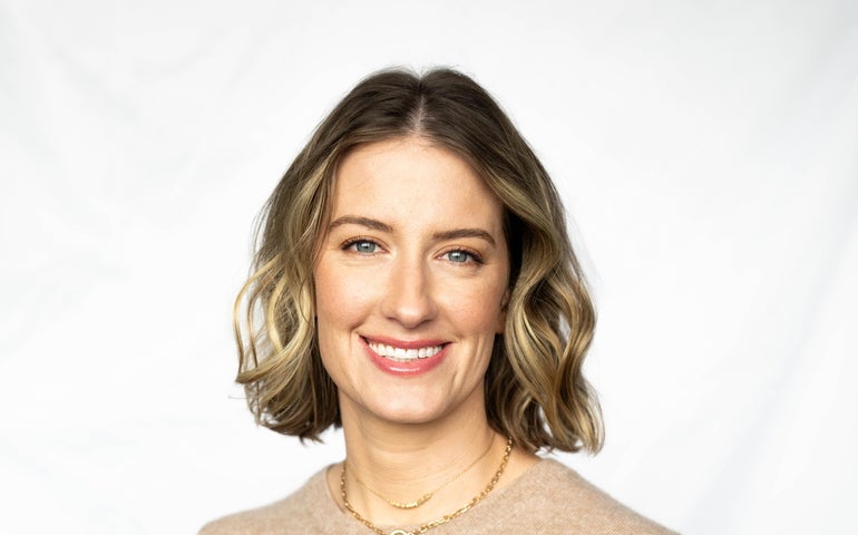 A woman stands in front of a white background