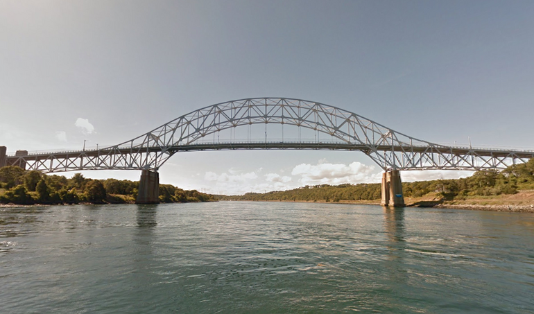 A large metal bridge spanning a large canal. 