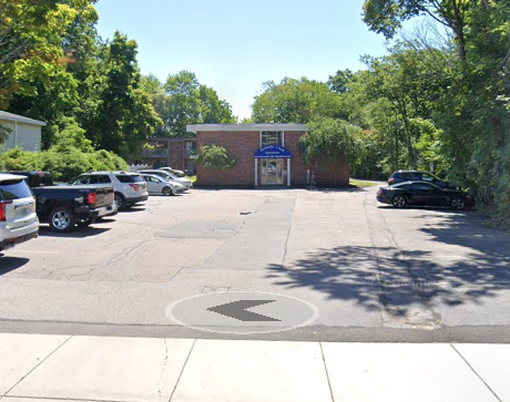 A small apartment building with a parking lot in front