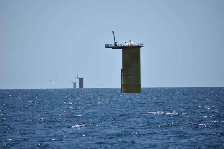 Three large metal pipes, with their tops sticking out about the ocean