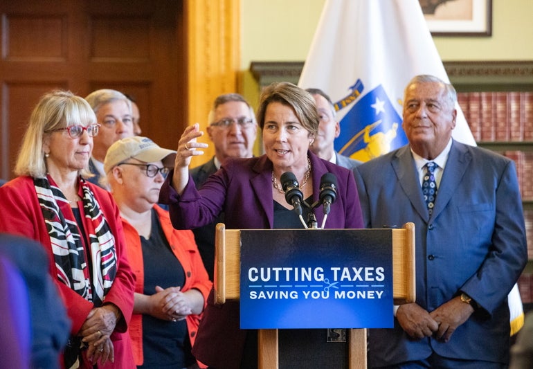 A woman speaks at a podium while a group of people stands behind her