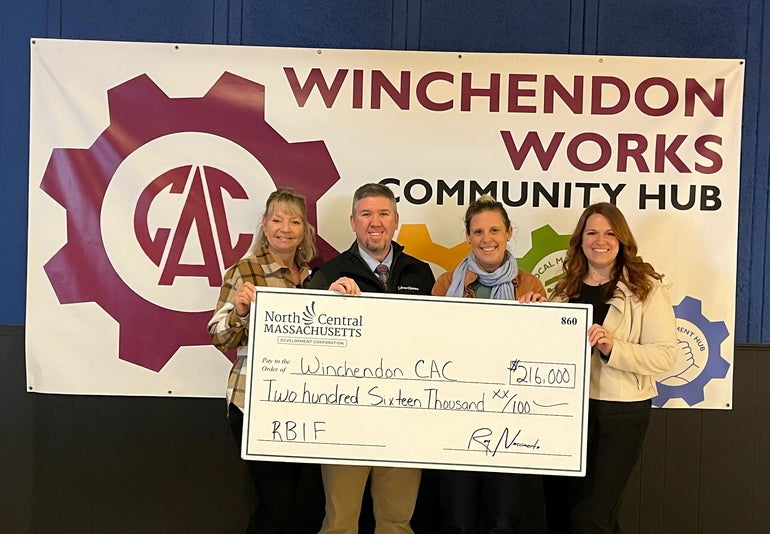 Four people standing with an oversized check