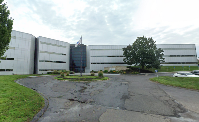 A large office building with a traffic circle and flag poles in front