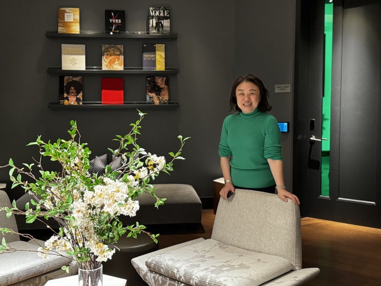 A woman stands behind a chair