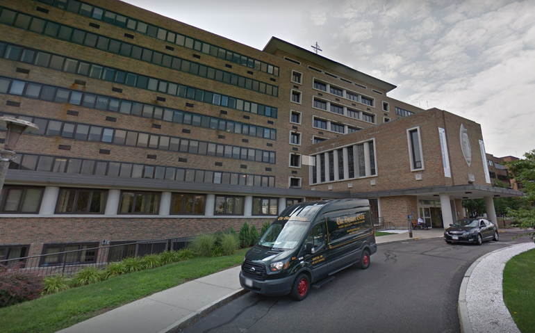 A large hospital building with a van parked in front