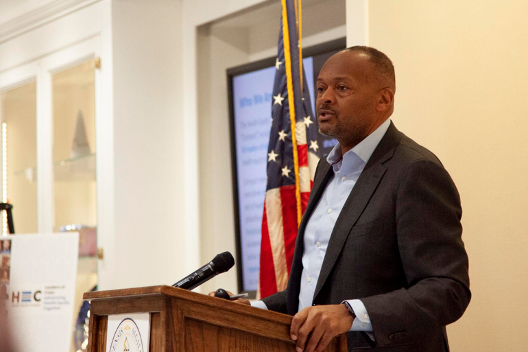 a man in a suit speaks at a podium