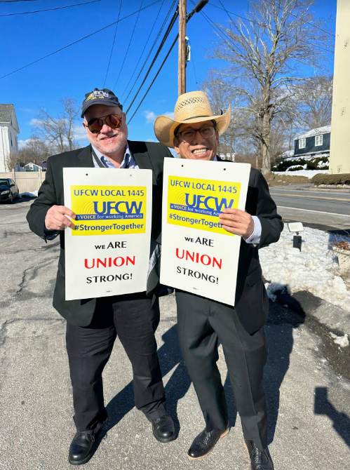 Two men, one in sun glasses and the other in a cowboy hat, hold union signs