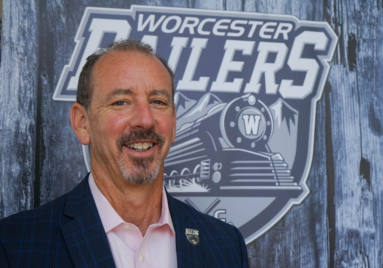 A man with a beard in a dark navy suit jacket and light pink shirt 