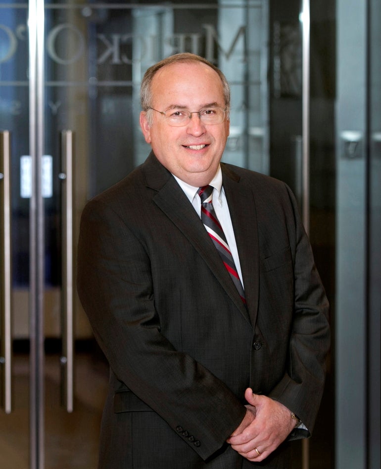 A man in a black suit and black, white, grey, and red striped tie