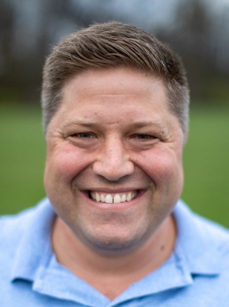 A man in a blue shirt smiles