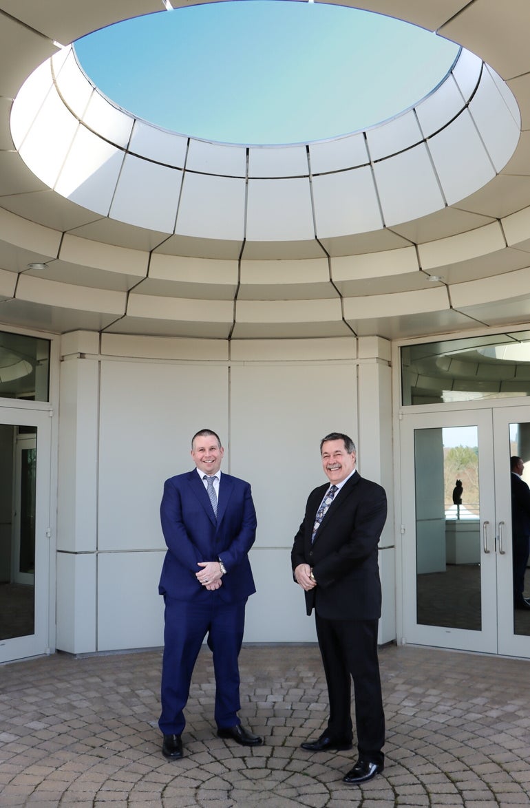 Two men in suits stand for a photograph