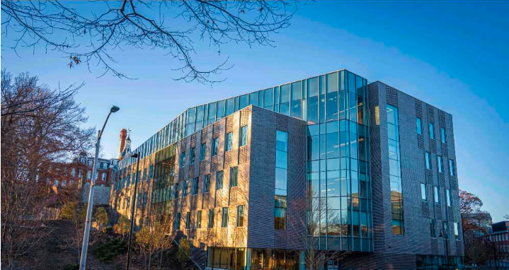 A large building with walls of windows in front of a clear blue sky 