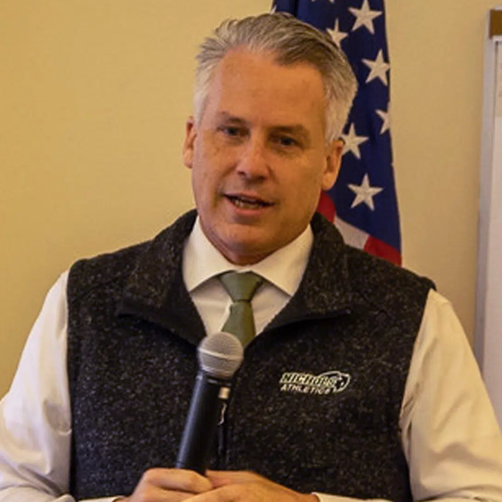 A man in sweater vest hold a microphone