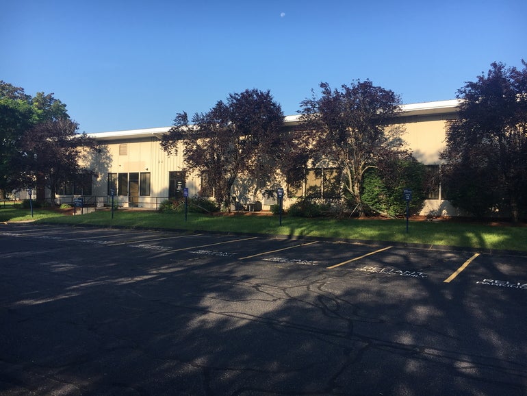 An industrial building with a parking lot in front. 