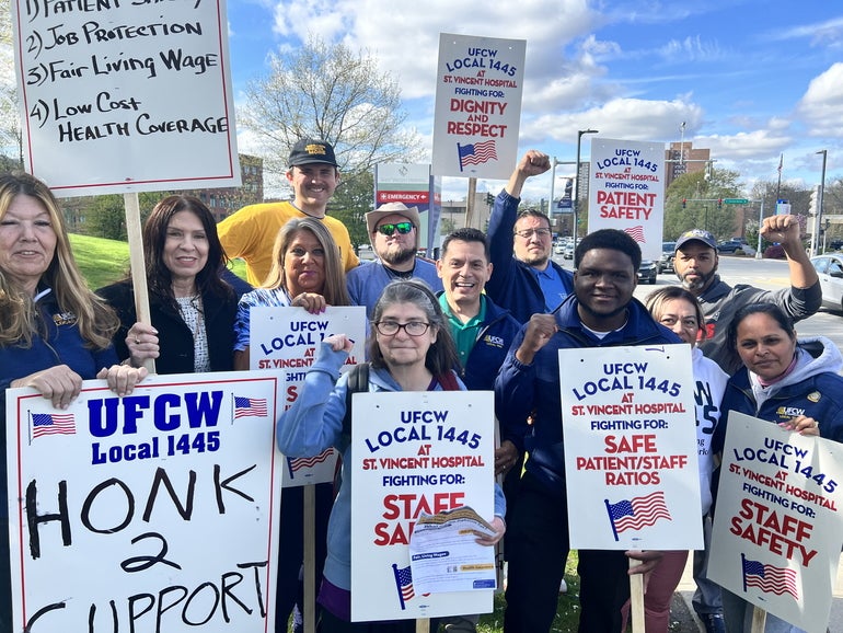 A group of people stand with signs, some holding up fists