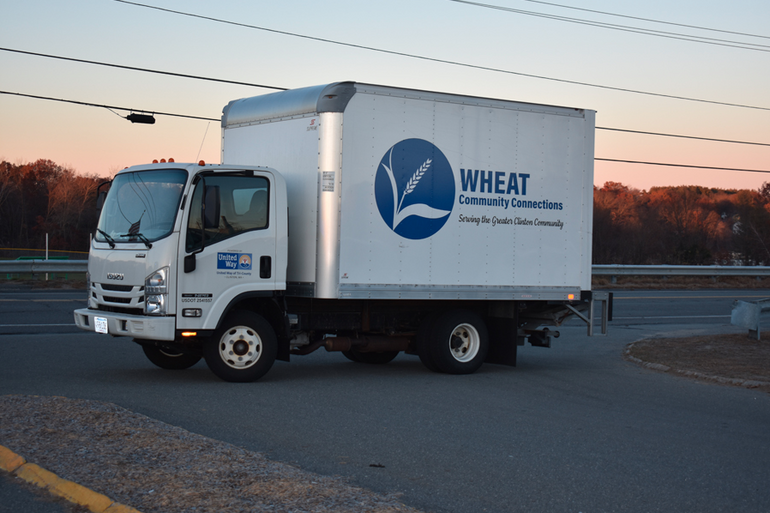 A white van with a blue logo of a plant sits on a road in front of a sunrise.