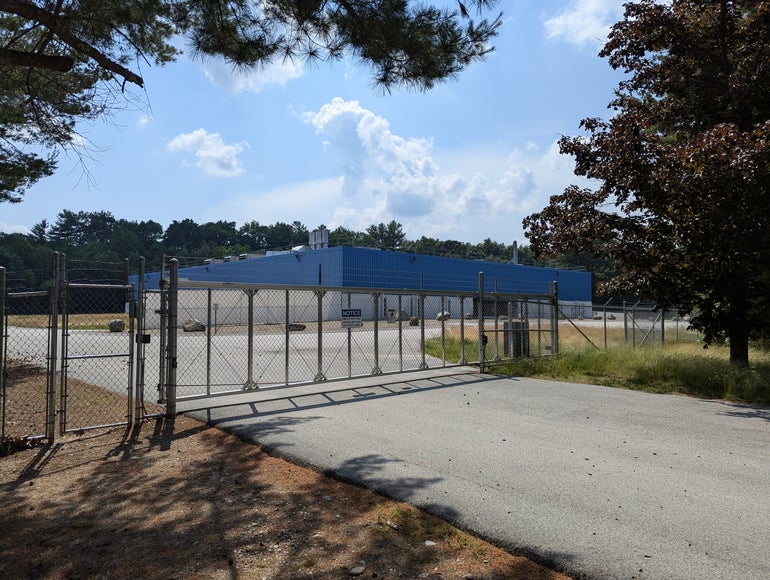 A blue industrial building behind a fence
