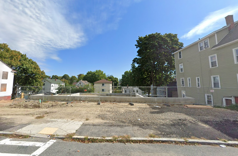 A lot with a foundation constructed on it, with a fence around it.