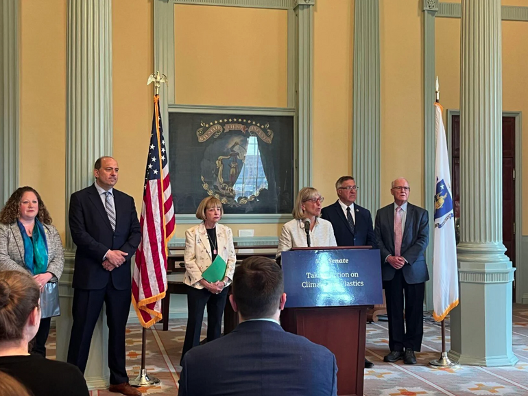 A group of legislators stand behind a podium