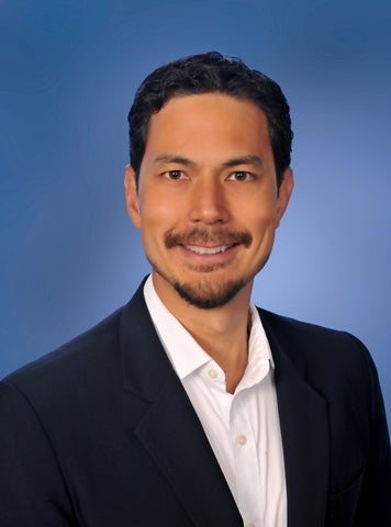 A man with a mustache in a suit jacket poses for a portrait photo
