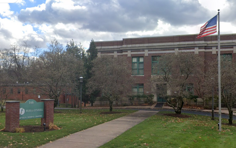 a two-story brick building with a sign and flagpole in front