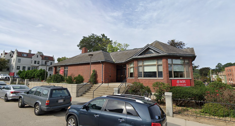 A brick building that appears to be one story, with cars parked on the street in front